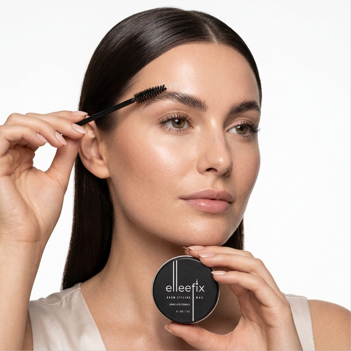 Brushing Elleebana Elleefix Brow Styling Wax through eyebrow hairs using a spoolie for a lifted, brushed-up brow look.